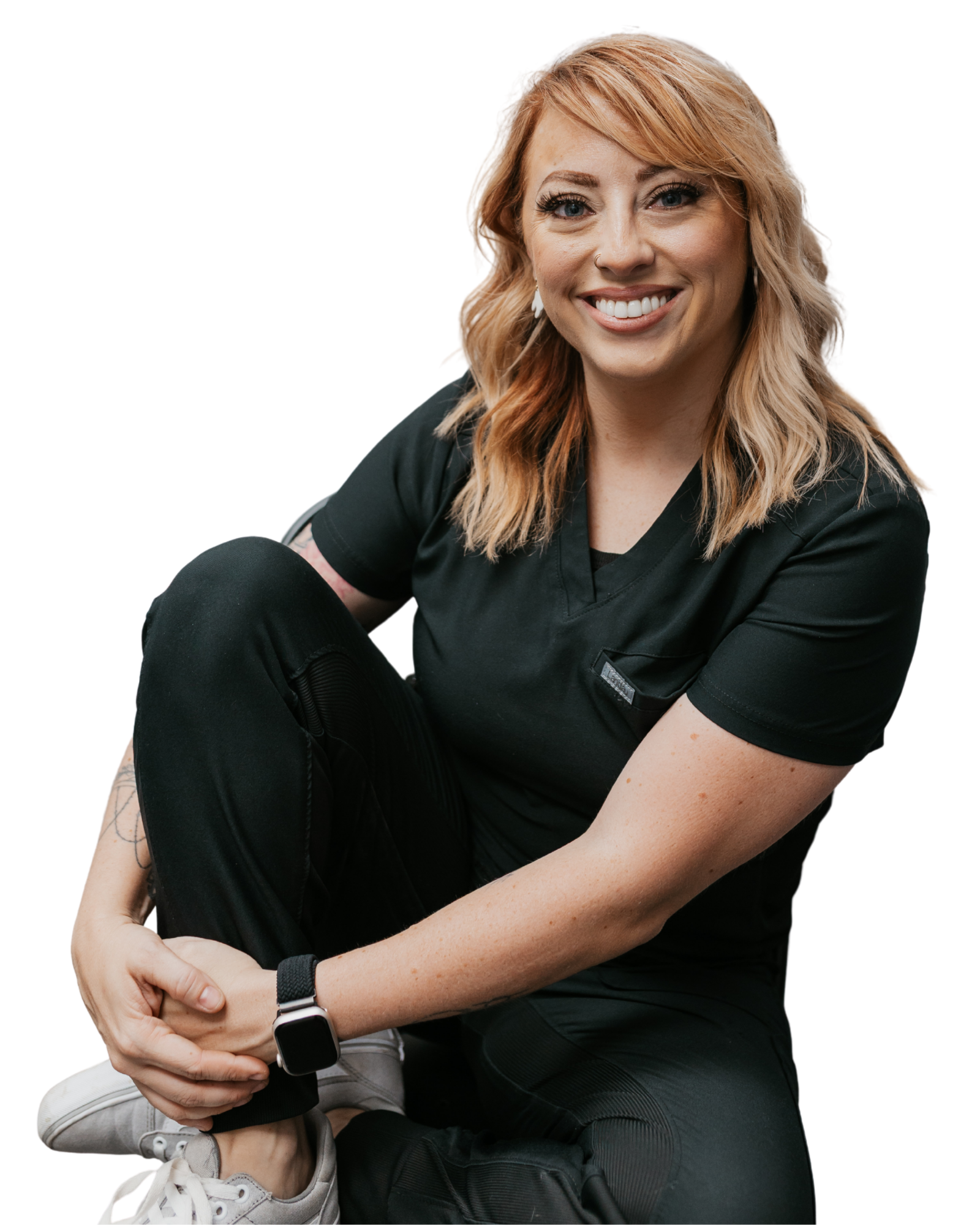 Smiling woman in black scrubs sitting cross legged on transparent background